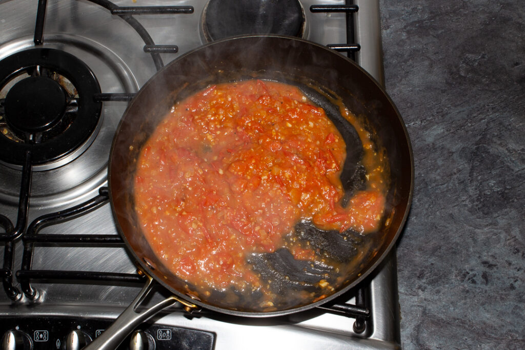 Tomato spaghetti sauce in a frying pan on the stove.