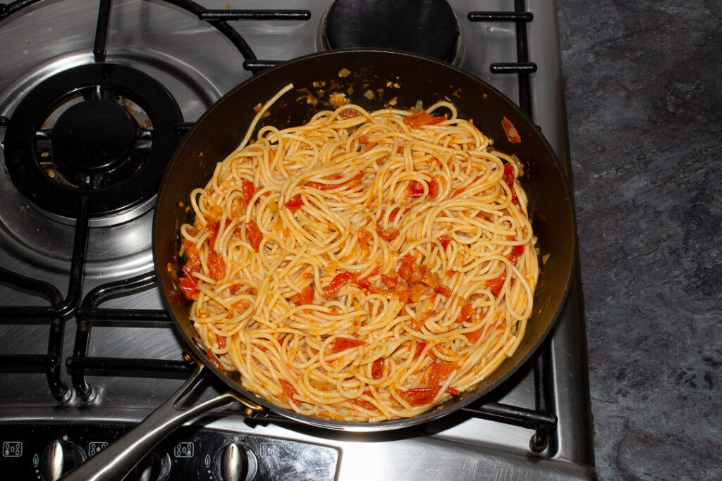 Tomato spaghetti in a frying pan on the stove