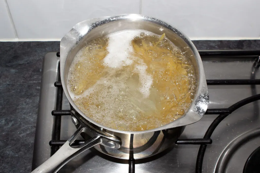 Spaghetti cooking in boiling water in a metal saucepan on the stove