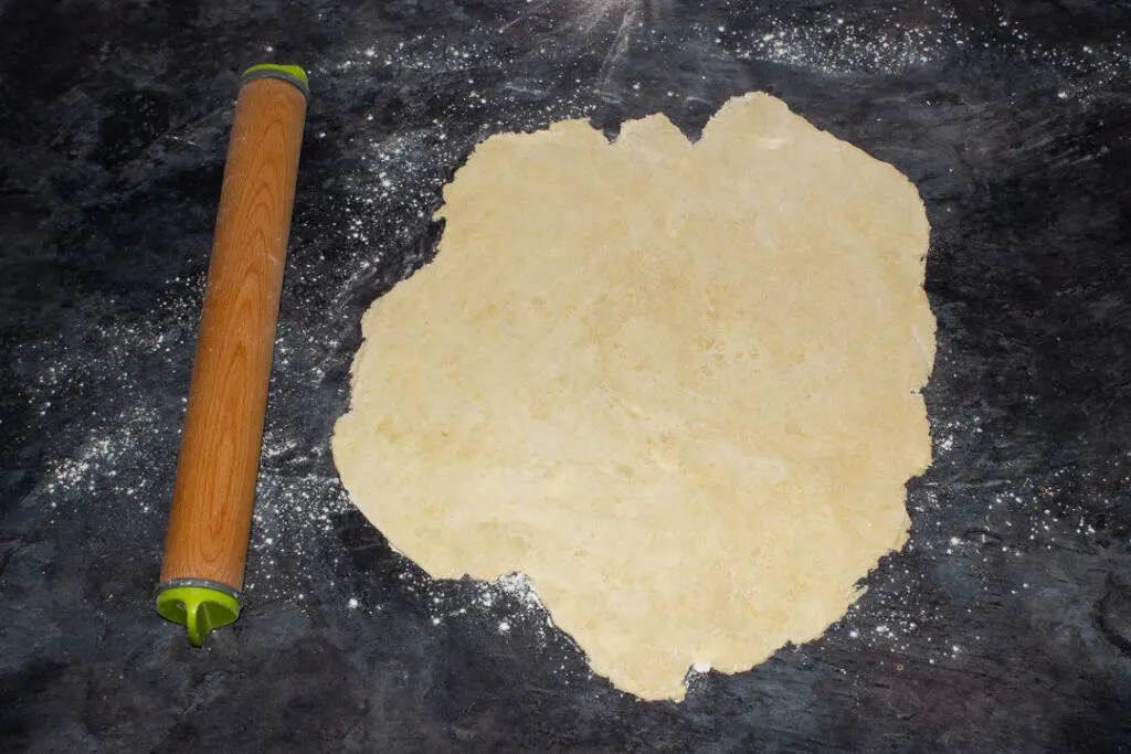 Shortcrust pastry rolled out on a floured worktop with a rolling pin