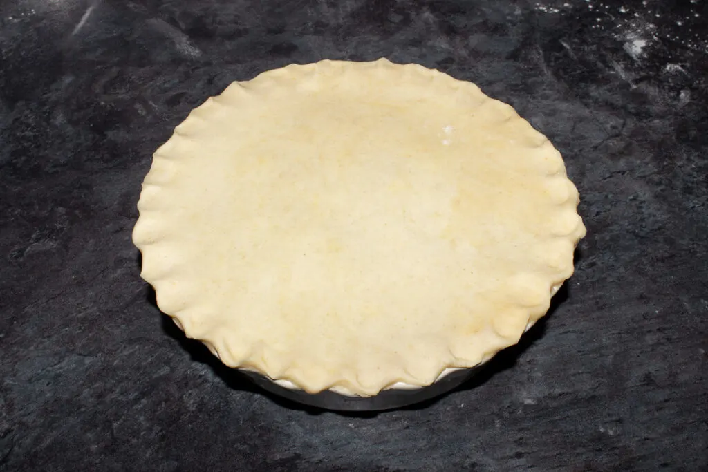 An unbaked vegetarian mince and onion pie with crimped edges
