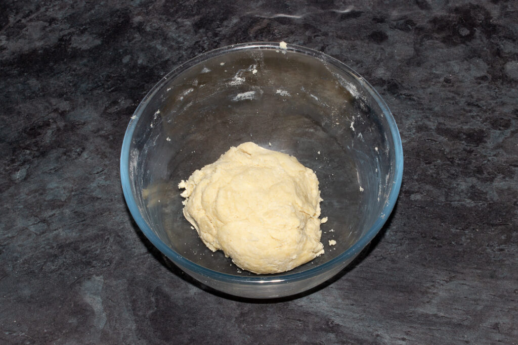 A scrappy ball of shortcrust pastry in a glass bowl