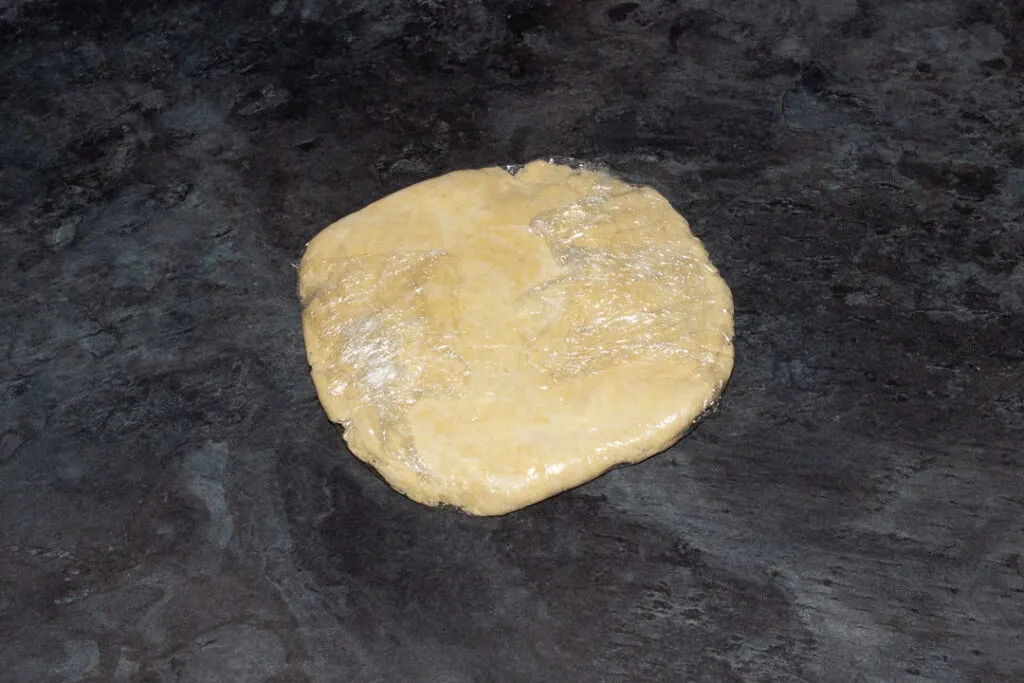 Shortcrust pastry wrapped in cling film flattened into a disc