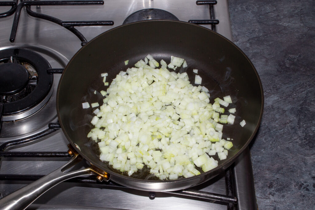 Diced onion frying in olive oil in a frying pan