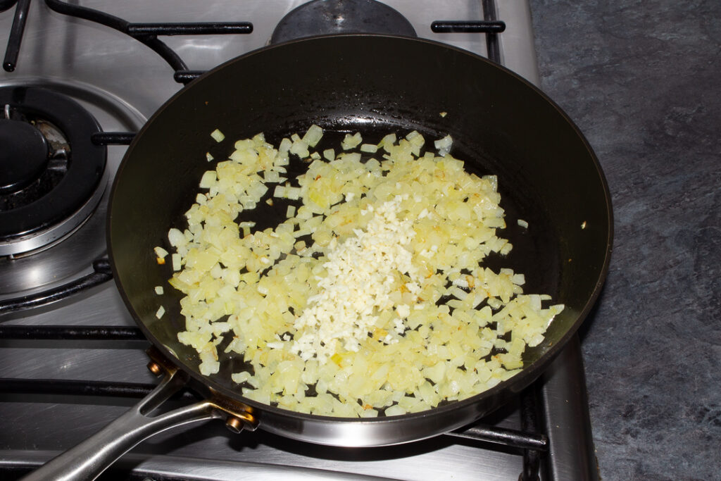 Cooked onion in a frying pan with minced garlic
