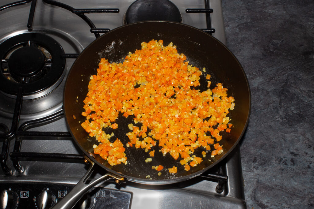 Onion, carrot, garlic and flour cooking in oil in a frying pan on the hob