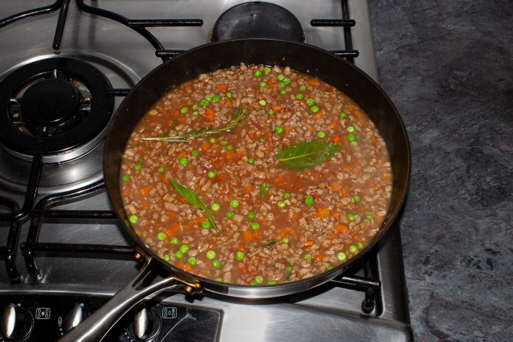 Vegetarian shepherd's pie mince ingredients all simmering together in a frying pan on the hob