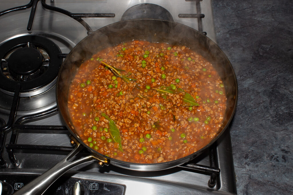 Vegetarian shepherd's pie mince ingredients all simmering together in a frying pan on the hob