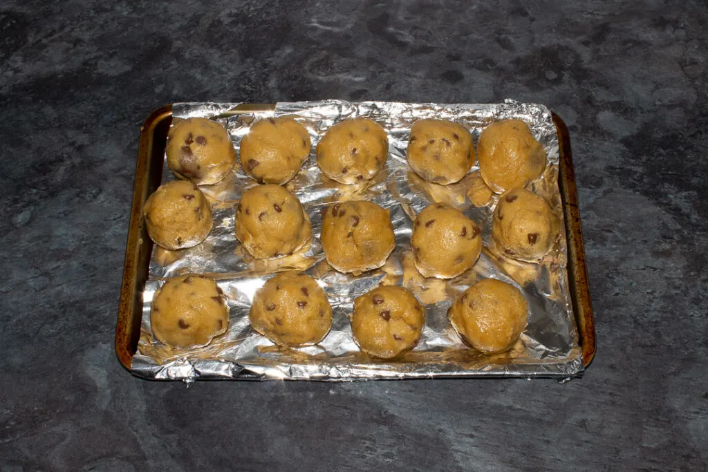 Creme Egg cookie balls on a foil lined baking tray