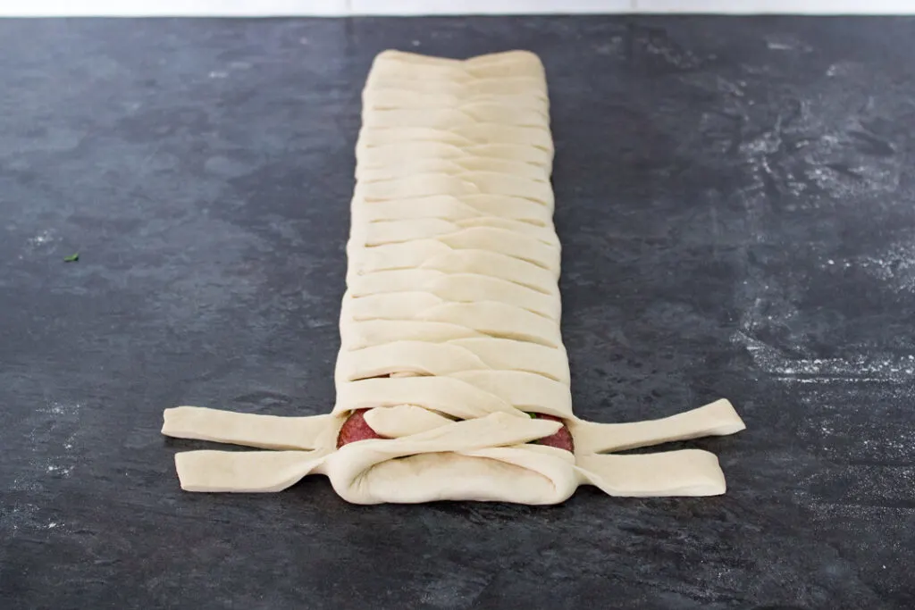 Pizza dough and fillings being folded into a latticed stromboli