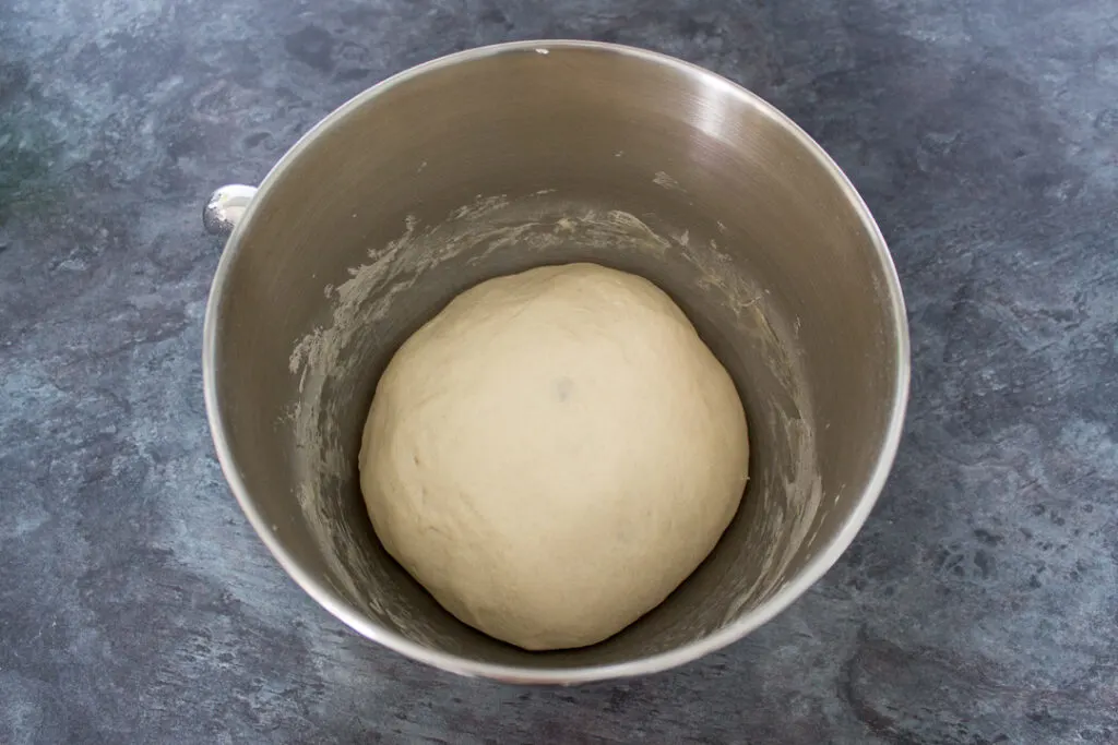 Risen pizza dough in the bowl of an electric stand mixer