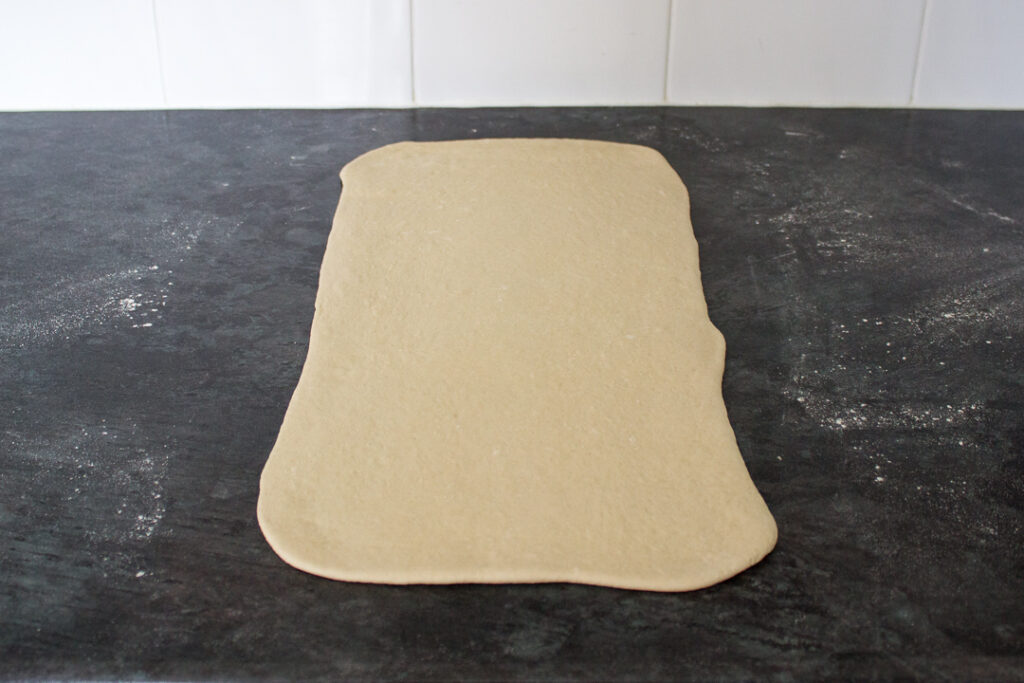 Pizza dough rolled out to a rectangle on a lightly floured work surface