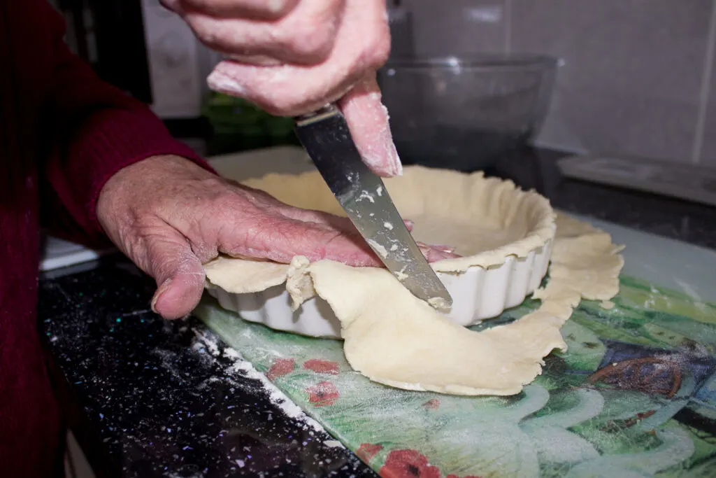 Gran trimming off the excess pastry with a knife