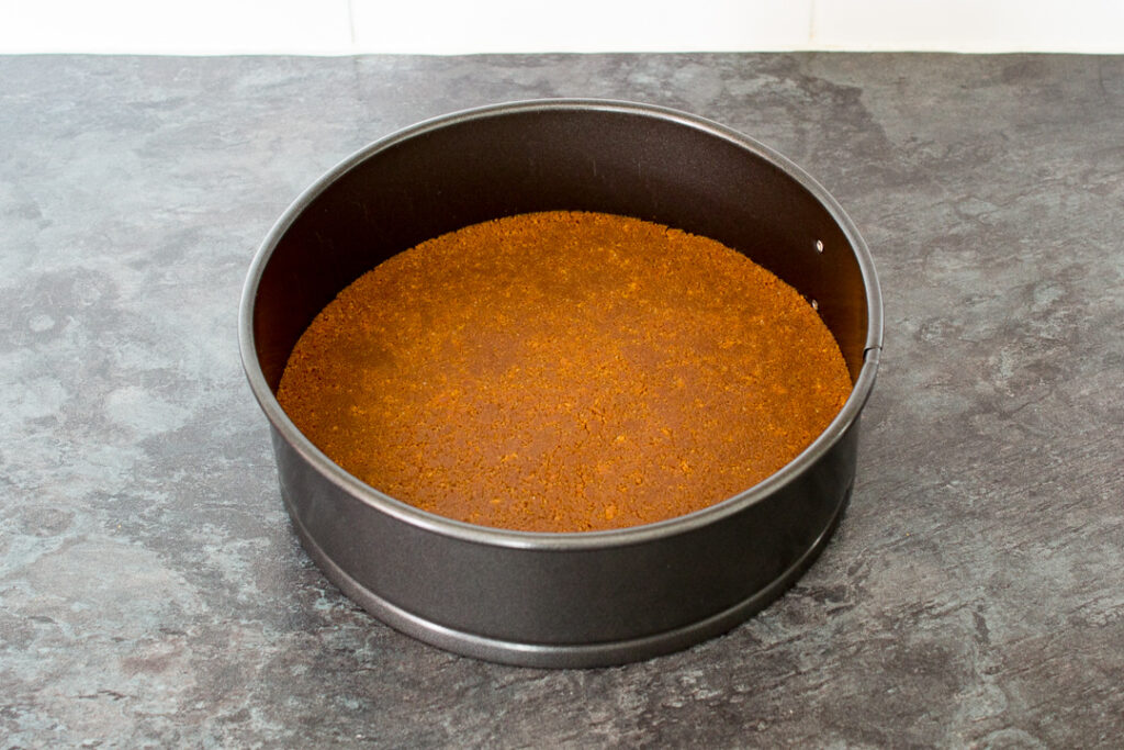 Biscoff cheesecake base pressed into a springform pan