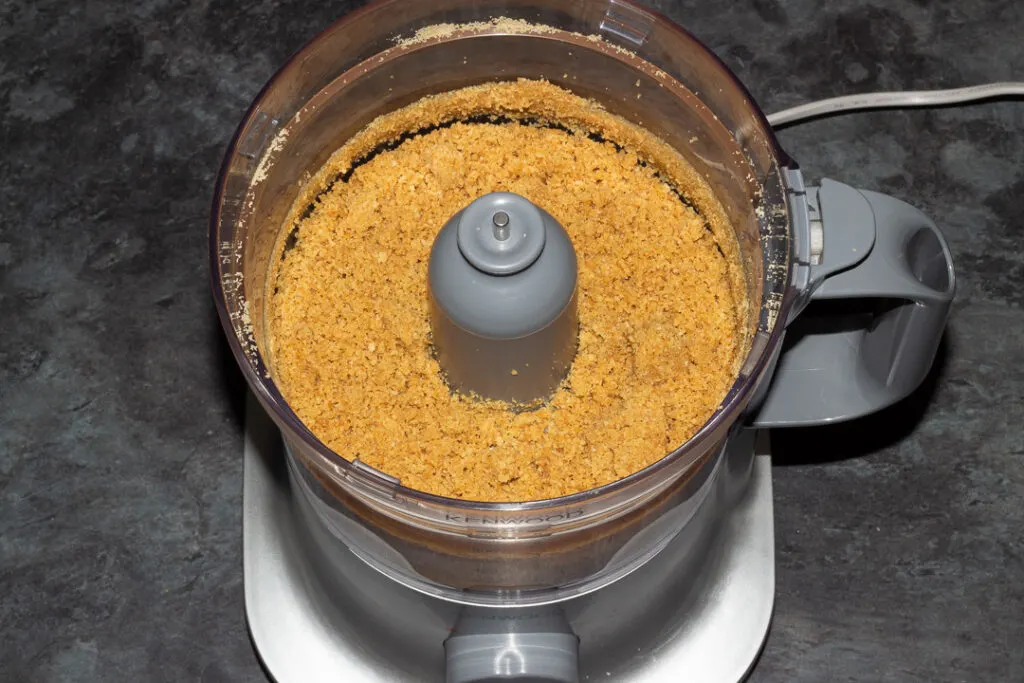 Clumpy biscuit crumbs and melted butter in a food processor