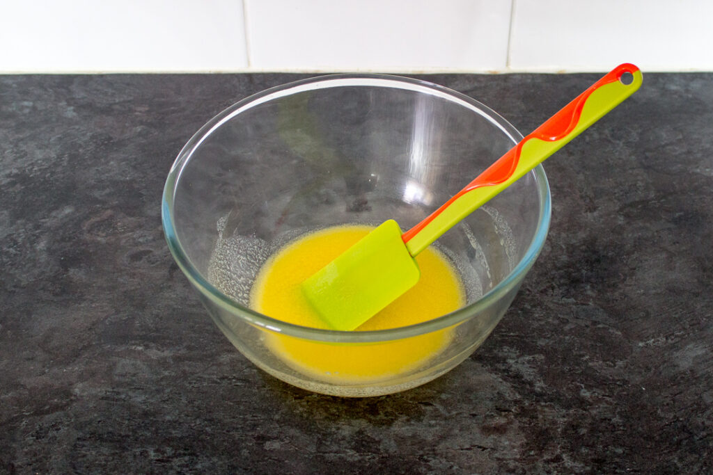 Melted butter in a glass bowl with a spatula.