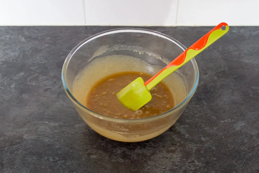 Melted butter, sugar, egg, vanilla and salt mixed together in a glass bowl with a spatula.