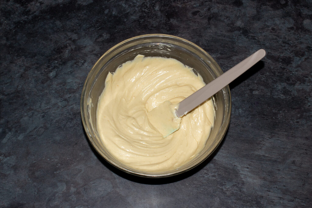 Cream cheese, sugar and malt powder beaten together in a mixing bowl with a spatula.