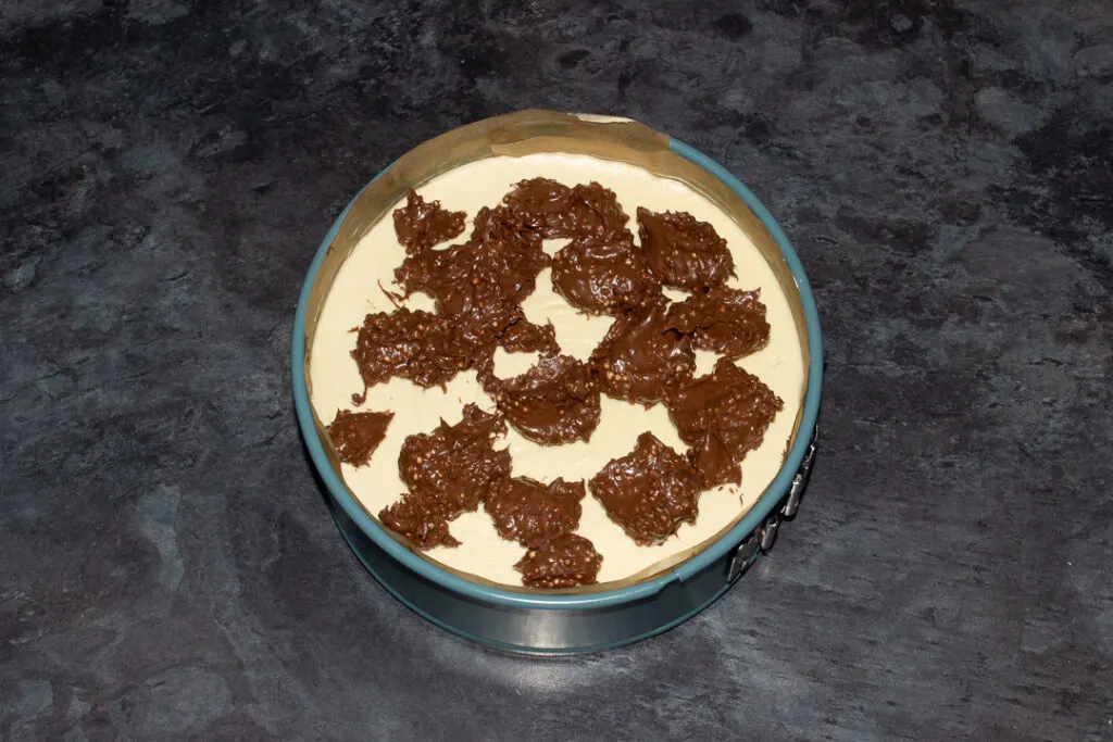 Blobs of Maltesers spread dotted around on the top of a set no bake Maltesers cheesecake.