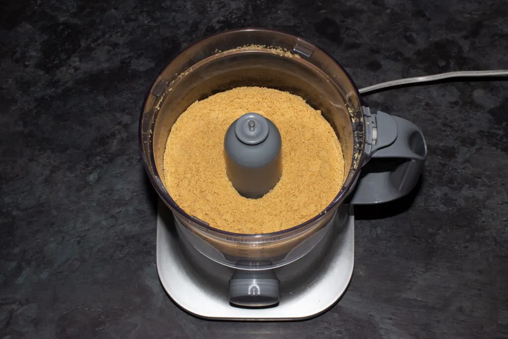 Crushed malted milk biscuits in a food processor on a kitchen worktop