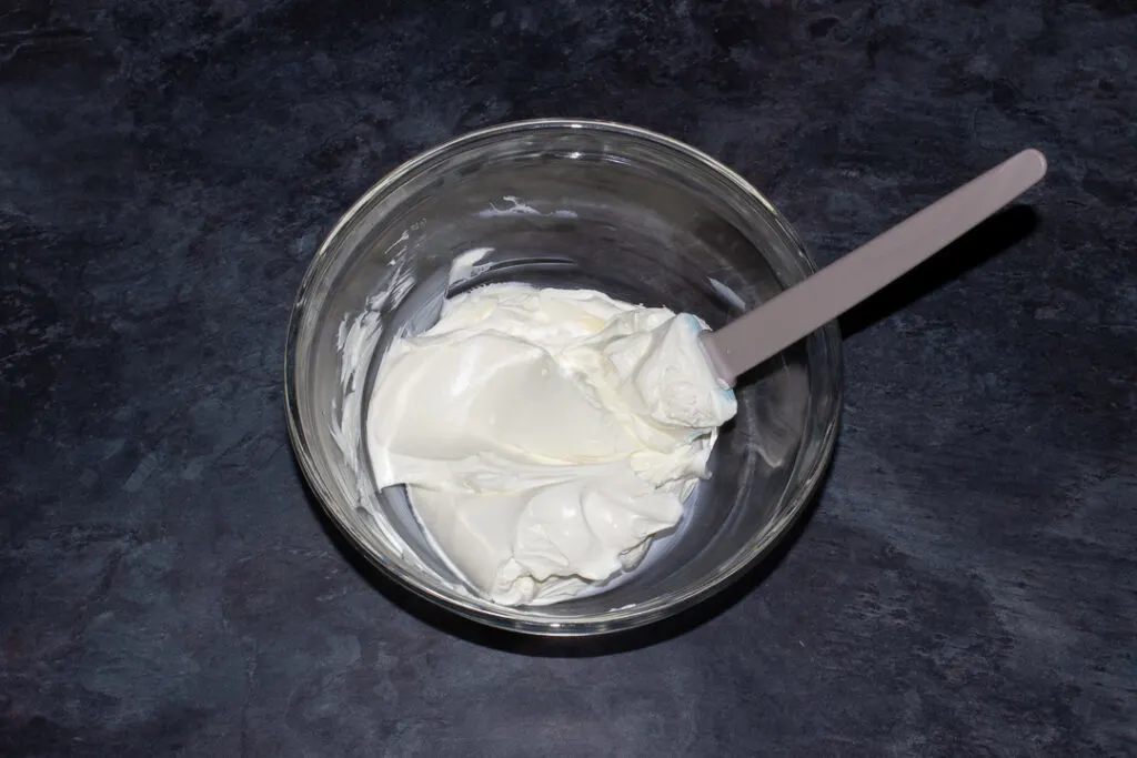 Softened cream cheese in a mixing bowl with a spatula.