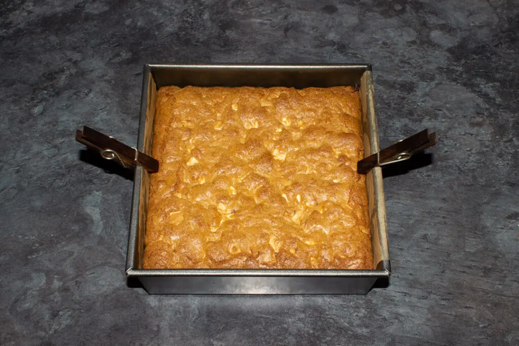 Baked white chocolate kinder nutella cookie bars cooling in a lined square baking tin