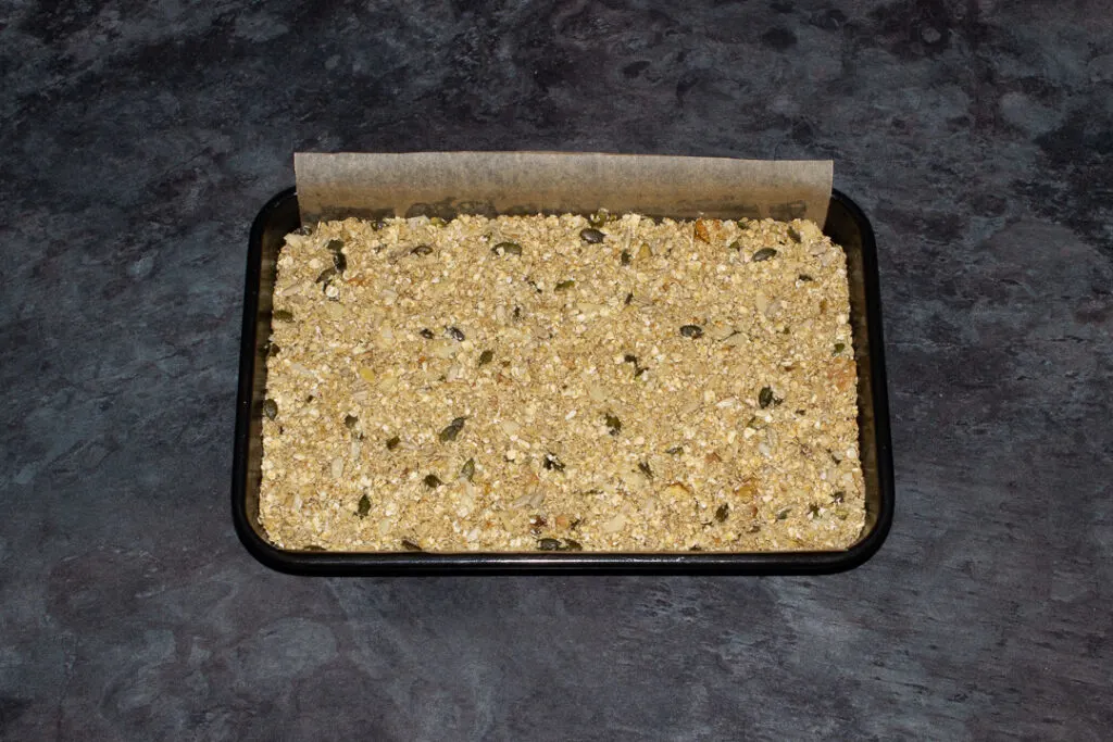 A lined rectangular tin with unbaked homemade granola inside.