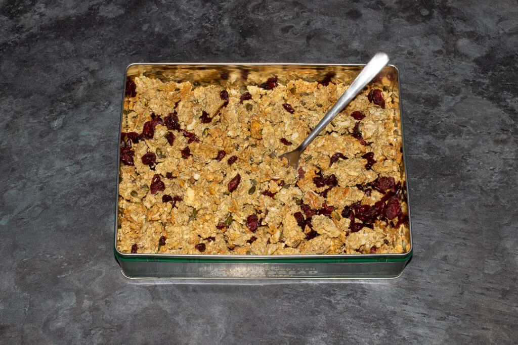 A metal tin with homemade granola and a fork inside.