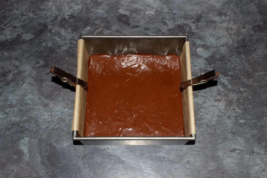 Twix brownie batter in a lined square baking tin.