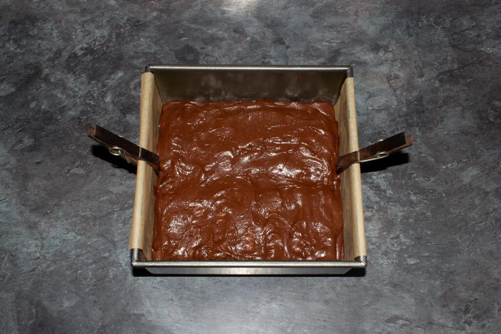 Twix brownies in a lined square baking tin ready to be baked.