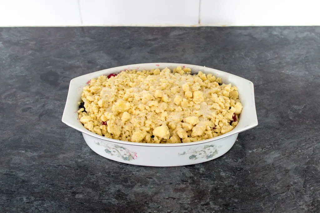 Apple berry Summer fruit crumble in an oven proof dish on a kitchen worktop, ready for the oven.
