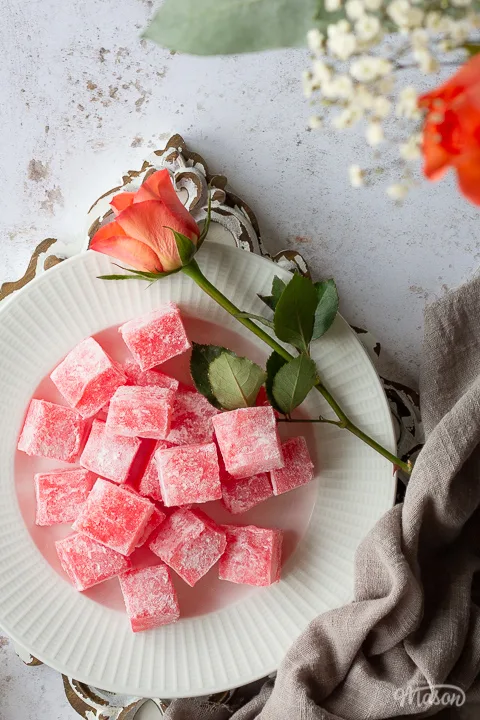 Close up of Turkish delight cubes on a plate with an orange flower