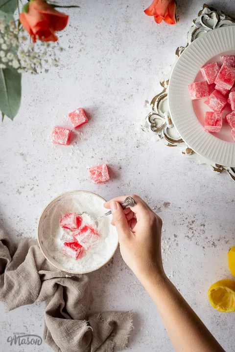 Someone coating Turkish delight in icing sugar over a linen napkin