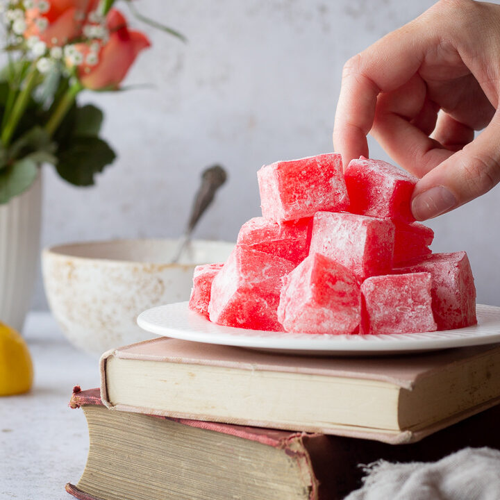 Someone taking a piece of Turkish delight from a plate on two stacked books