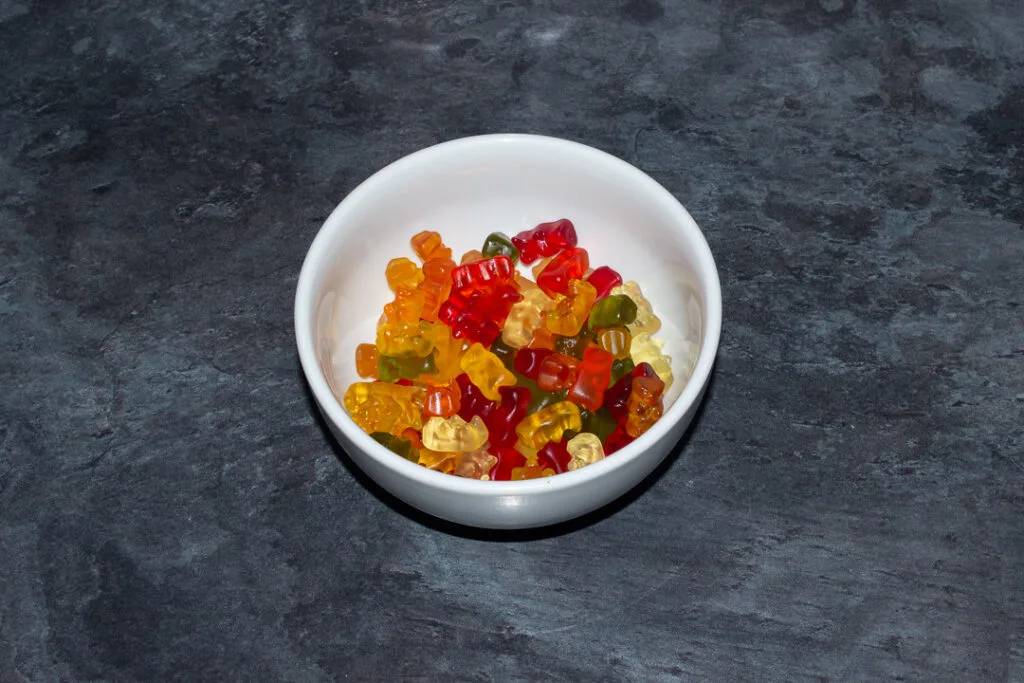 Gummy bears in a white bowl on a kitchen worktop.