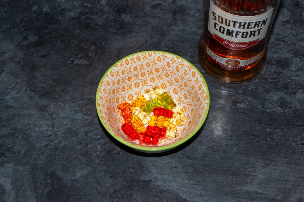 Rinsed Southern Comfort soaked gummy bears in a bowl on a kitchen worktop. There's a bottle of Southern Comfort in the background.