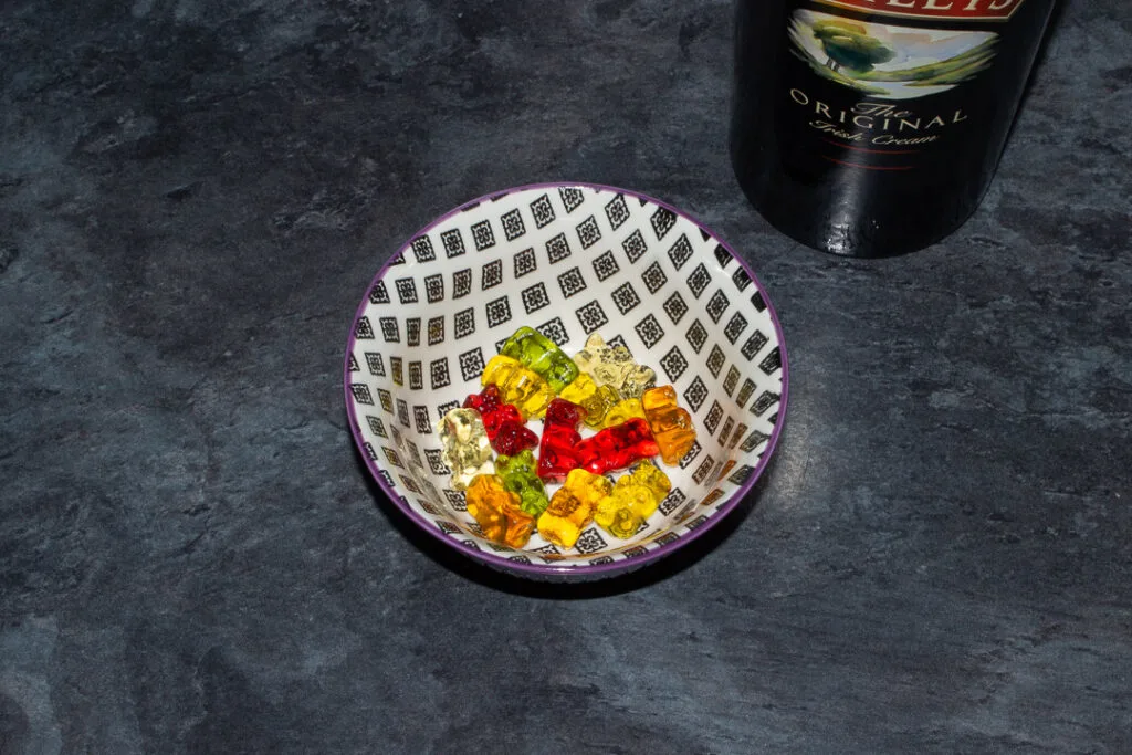 Rinsed Baileys soaked gummy bears in a bowl on a kitchen worktop. There's a bottle of Baileys in the background.