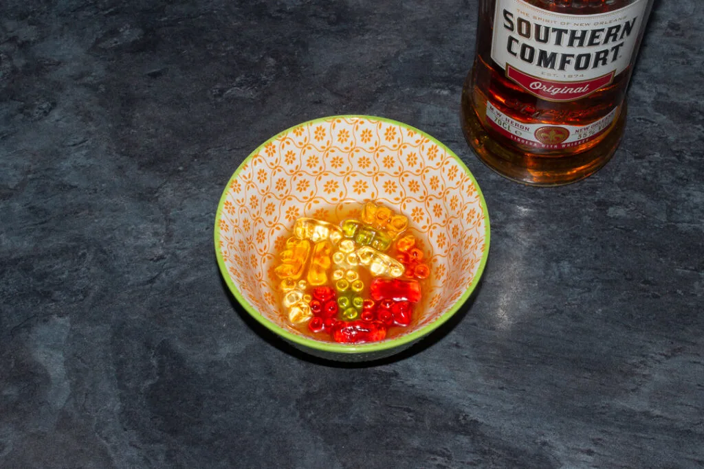 Gummy bears soaked in Southern Comfort in a bowl on a kitchen worktop. There's a bottle of Southern Comfort in the background.