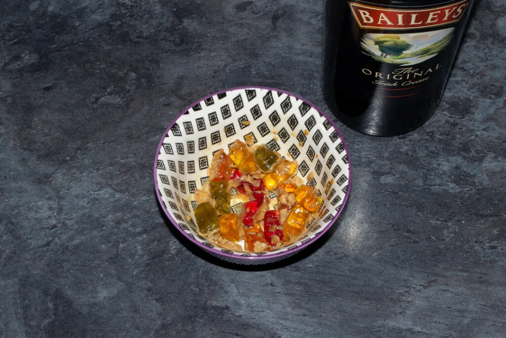Gummy bears soaked in Baileys in a bowl on a kitchen worktop. There's a bottle of Baileys in the background.
