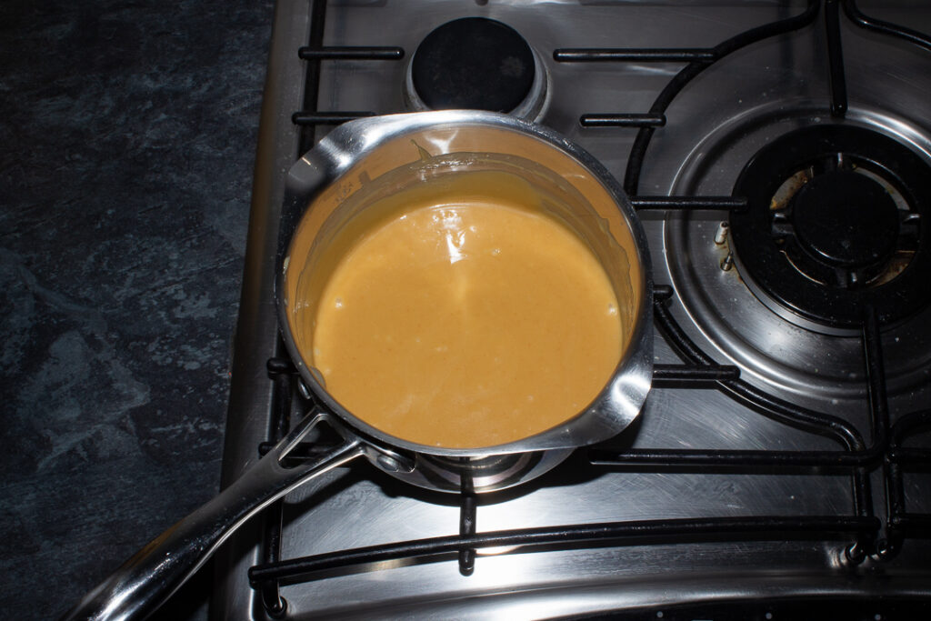 Cooked caramel in a saucepan on a stove top.