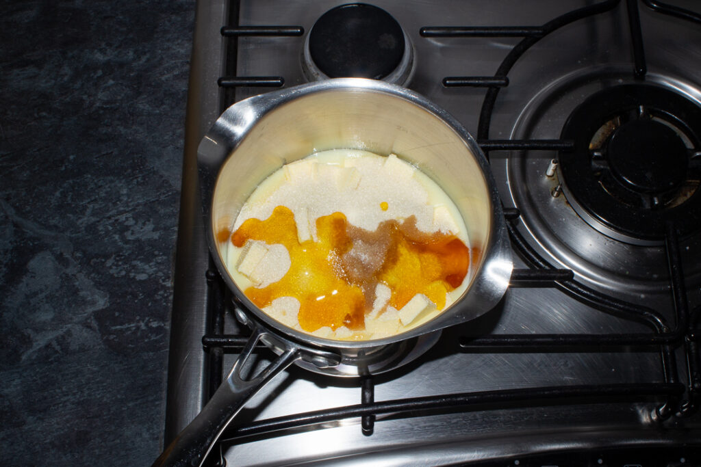 Condensed milk, butter, sugar, golden syrup, vanilla and salt in a saucepan set over a low heat on a stove top.