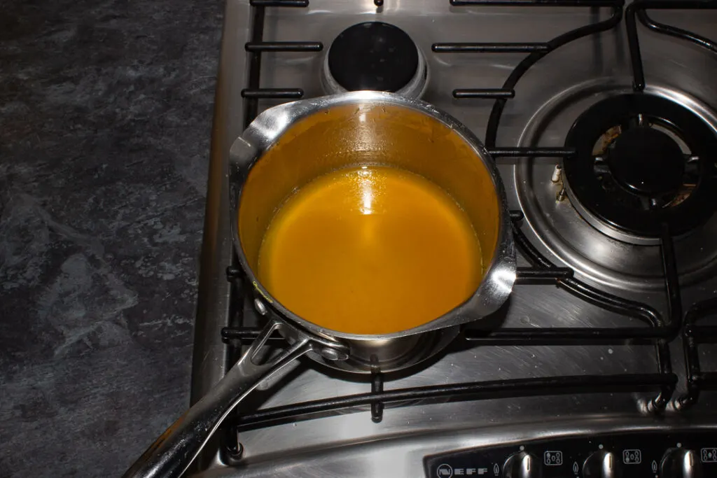 Orange syrup in a saucepan on the stove top.
