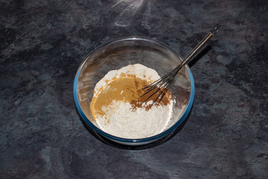 A large mixing bowl filled with ginger, cinnamon and flour on a kitchen worktop.