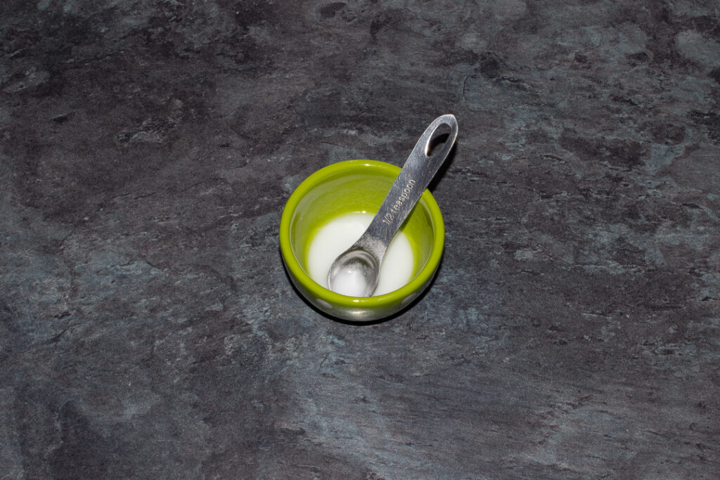 A small green pot filled with bicarbonate of soda dissolved in water set on a kitchen worktop.