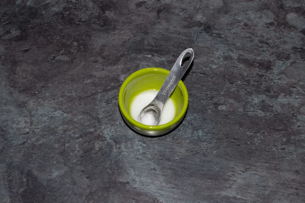 A small green pot filled with bicarbonate of soda dissolved in water set on a kitchen worktop.