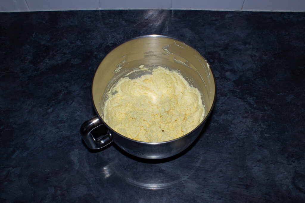Beaten butter, sugar and eggs in the bowl of an electric stand mixer on a kitchen worktop.