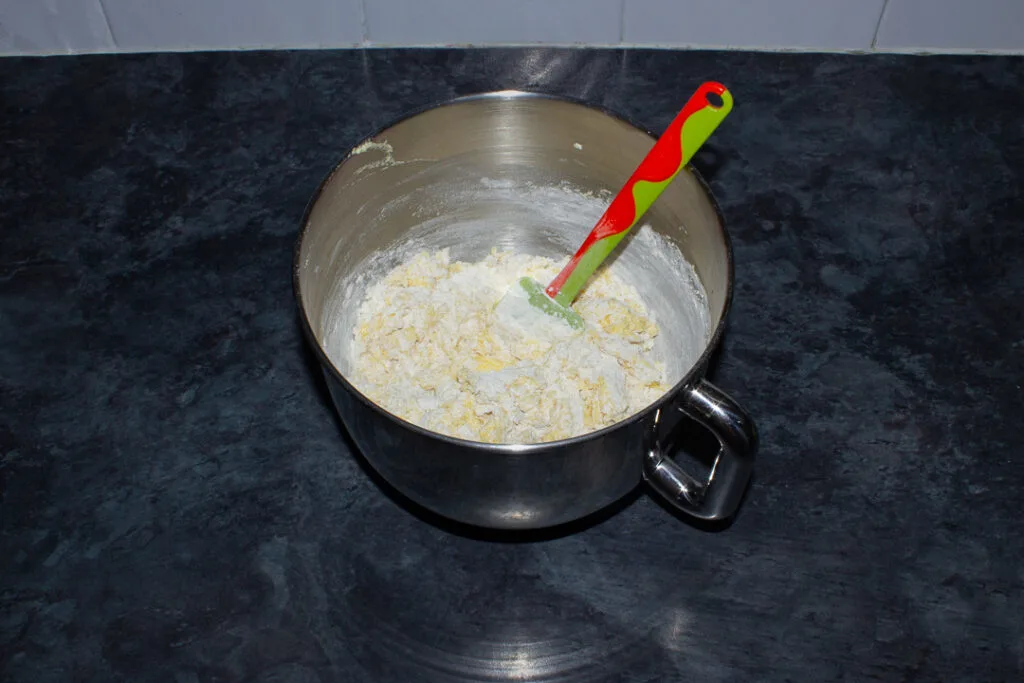 Beaten butter, sugar, eggs, lemon zest, flour and baking powder in the bowl of an electric stand mixer on a kitchen worktop.