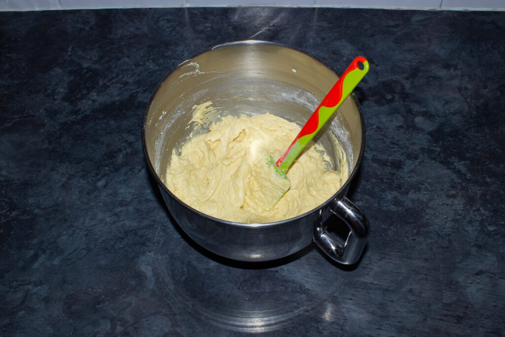 Lemon drizzle cake batter in the bowl of an electric stand mixer on a kitchen worktop.