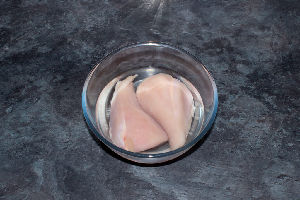 2 large chicken breasts in a bowl of salt water (brine).