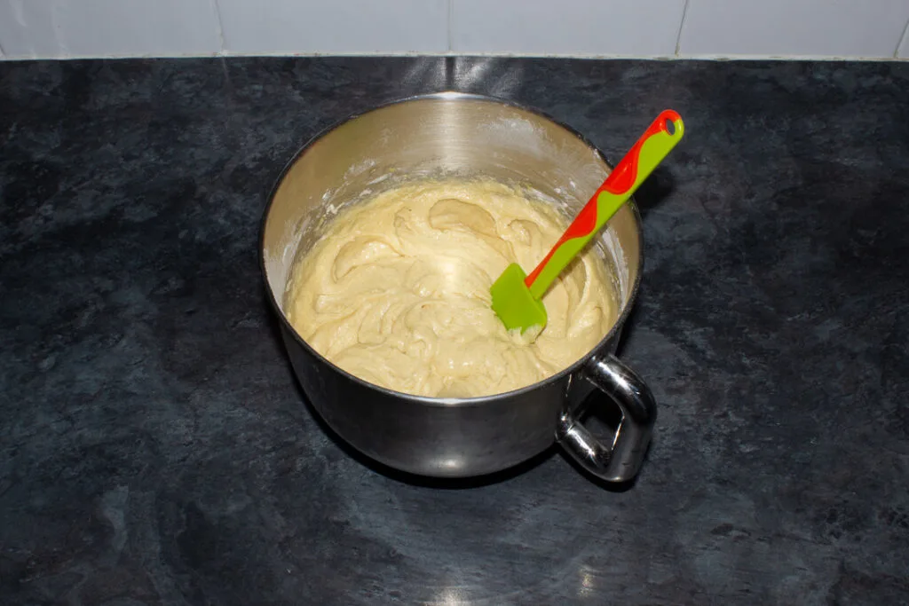 Biscoff cake batter in an electric stand mixer bowl with a spatula.